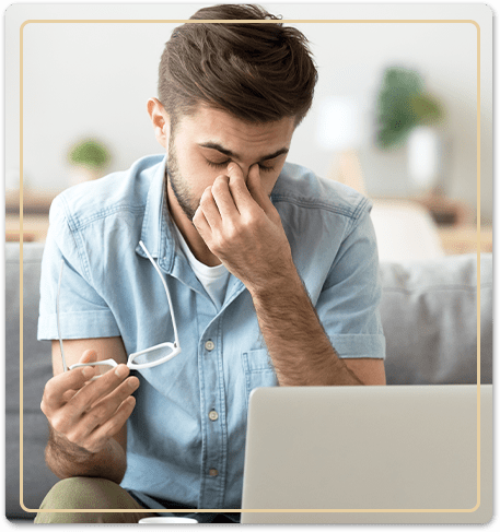 man in blue shirt rubbing eyes